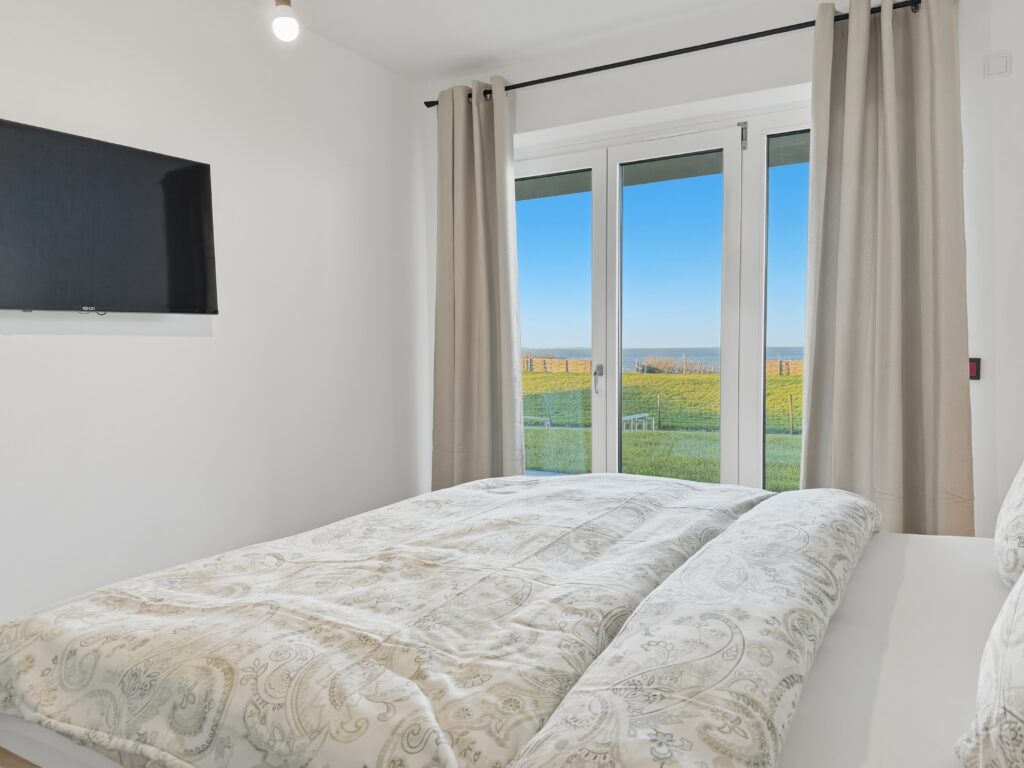 Das Schlafzimmer der Ferienwohnung verfügt über hochwertige Matratzen, Meerblick und einen Flachbildschirm